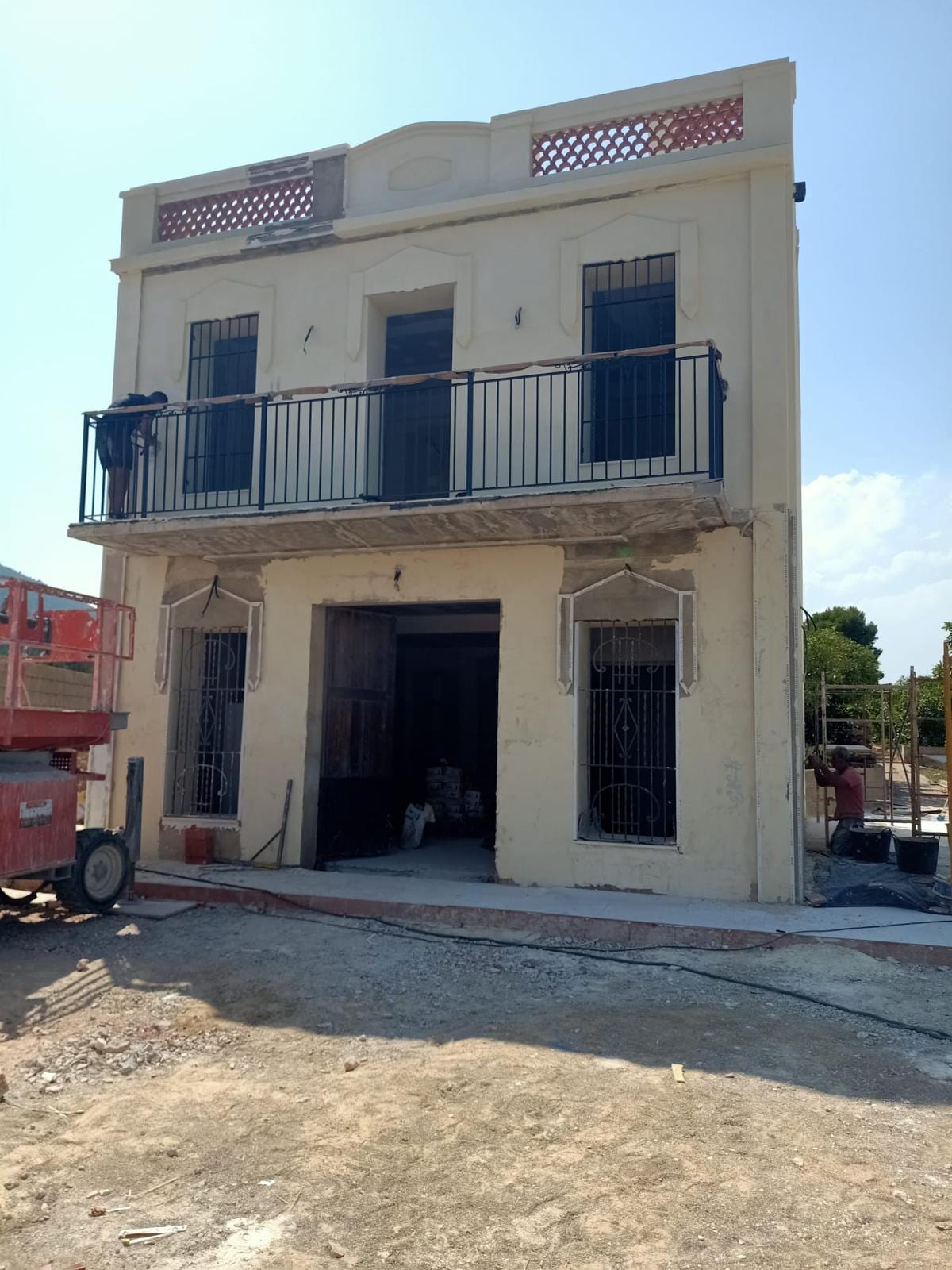 fachada de casa antigua con balcón corrido de barandilla negra y rejas en planta baja