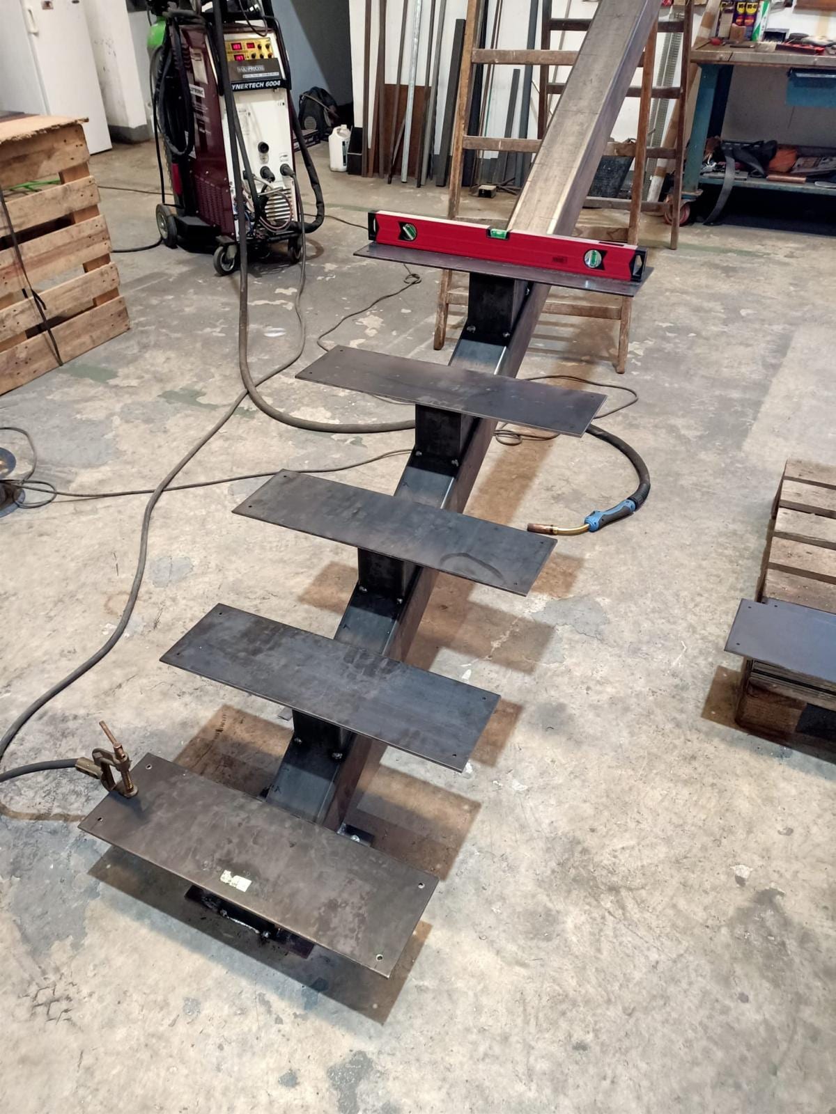 escalera de zanca central con peldaños de chapa en fabricación, con nivel encima